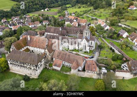 Blick aus der Vogelperspektive auf die rot gekachelten Dächer und Steinmauern des Klosters Bebenhausen, eingebettet in üppige grüne Felder und malerische Dorfhäuser, Tubingen, Baden-WUR Stockfoto