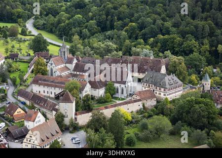 Die rot gefliesten Dächer und Steinmauern des Klosters Bebenhausen aus der Vogelperspektive stehen im Kontrast zum tiefgrünen Wald, eingerahmt von gewundenen Straßen, Tubingen, Bad Stockfoto