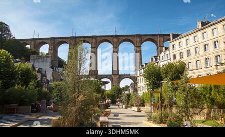 Grüner Stadtpark mit Wanderwegen und einem beeindruckenden Viadukt als malerische Kulisse. Stockfoto