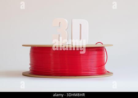 Rotes Kunststofffilament für 3D-Druck auf einer Spule und weißen volumetrischen 3D-Text, ein Kilogramm Spooling auf weißem Hintergrund, 3D-Druckermaterial Stockfoto