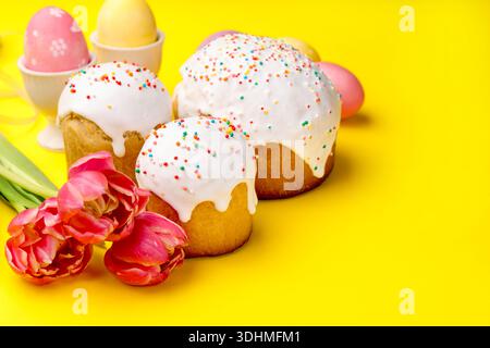 Köstliche Osterkuchen, Eier und Tulpen auf gelbem Hintergrund, Nahaufnahme Stockfoto