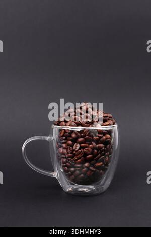 Glasbecher voller Bohnenkaffee isoliert auf schwarzem Hintergrund. Kaffeemaschine Stockfoto