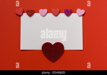 Romantischer Valentinstag Hintergrund mit rosa und roten Herzen und leerem Papierbogen für Text. Grußkartenvorlage mit Kopierraum. Stockfoto