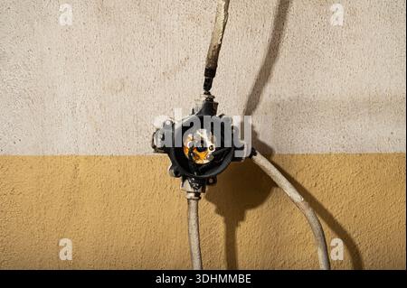 Nahaufnahme des offenen elektrischen Anschlusskastens mit freiliegender Verkabelung an der Wand. Konzept der Elektroinstallation, Wartung, Sicherheitsrisiken und Unfinis Stockfoto