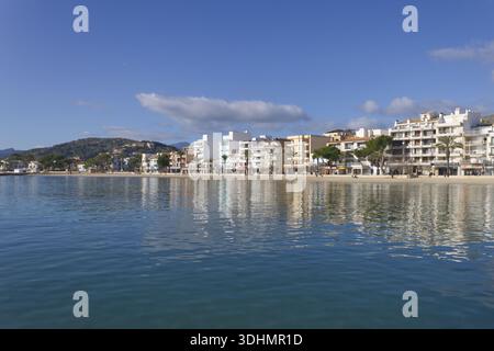 Reflexionen von Hotels am Meer im ruhigen Wasser von Port de Pollenca an einem hellen Wintertag auf Mallorca. Stockfoto