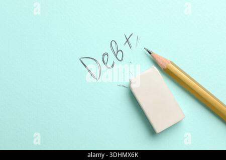 Löscht Wort Schulden geschrieben mit Bleistift auf türkisfarbenem Hintergrund, Nahaufnahme Stockfoto