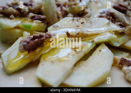 Makrotextur von geschnittenen grünen Äpfeln gemischt mit Walnüssen und braunem Zucker. Saftiger Fruchtkuchen mit Füllung. Stockfoto