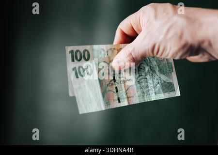 Banknoten der tschechischen Krone zwischen den Fingern. Konzept der Bargeldabwicklung, Konsumausgaben, Einsparungen und alltägliches Geldmanagement Stockfoto