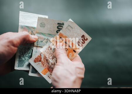Hände, die eine tschechische Kronen-Banknote vor neutralem Hintergrund halten. Konzept der Geldwirtschaft, des finanziellen Bewusstseins, der Inflation und der persönlichen Stockfoto