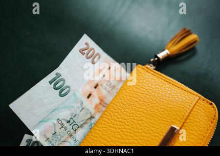 Nahaufnahme von tschechischen Kronen-Banknoten, die teilweise aus einer gelben Ledergeldbörse gezogen wurden. Persönliche Finanzen, tägliche Ausgaben, Barzahlungen, Budgetierung und Stockfoto