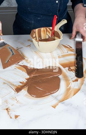 Eine Konditorin, die Schokolade auf einer Marmorplatte vergütet. Stockfoto
