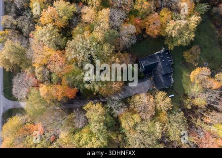 Blick auf ein Haus, das von Herbstwald umgeben ist, von oben nach unten, mit Herbstlaub, Baumkronen und dem Verhältnis zwischen Natur und Natur Stockfoto