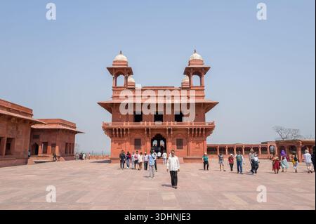 Fatehpur Sikri, Indien - 12. März 2024: Das Bild zeigt den roten Sandstein Diwan-i-Khas-Saal mit vier Chhatris und Gruppen von Menschen, die im offenen Innenhof des Palastkomplexes bei Fatehpur Sikri spazieren. Stockfoto