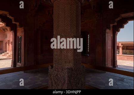 Fatehpur Sikri, Indien - 12. März 2024: Das Bild zeigt eine Nahaufnahme der aufwändig geschnitzten zentralen Sandsteinsäule mit geometrischen und floralen Mustern in der Diwan-i-Khas Halle des Palastkomplexes in Fatehpur Sikri. Stockfoto