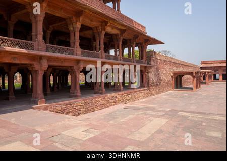 Fatehpur Sikri, Indien - 12. März 2024: Das Bild zeigt den mehrstöckigen Pavillon aus rotem Sandstein Panch Mahal mit Säulenreihen und komplizierten Steingittern, der sich innerhalb des Palastkomplexes in Fatehpur Sikri mit einem offenen Innenhof im Vordergrund befindet. Stockfoto