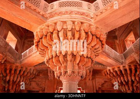 Fatehpur Sikri, Indien - 12. März 2024: Das Bild zeigt die aufwändig geschnitzte zentrale Sandsteinsäule mit strahlenden Klammern, die die obere Galerie in der Diwan-i-Khas-Halle des Palastkomplexes in Fatehpur Sikri stützen. Stockfoto