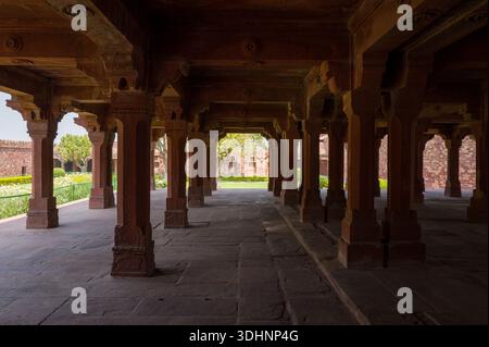 Fatehpur Sikri, Indien - 12. März 2024: Das Bild zeigt das Erdgeschoss des Panch Mahal Pavillons mit Reihen von roten Sandsteinsäulen und geschnitzten Klammern, Teil des Palastkomplexes bei Fatehpur Sikri, mit freiem Blick auf den Garten und den Innenhof. Stockfoto