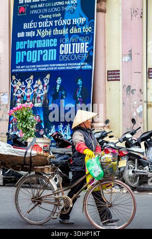 Straßenverkäufer mit Bambushut auf der Straße vor dem Eingang des Hanoi Cai Luong Theatre, Vietnam Stockfoto