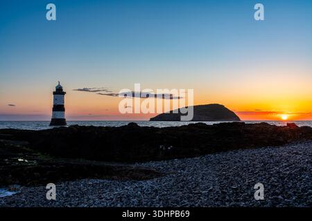 Sonnenaufgang am Penmon Point mit Trwyn du Lighthouse und Puffin Island am Horizont Stockfoto