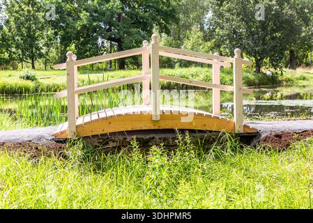 Kleine Holzbrücke mit Geländer im Park an sonnigen Sommertagen Stockfoto