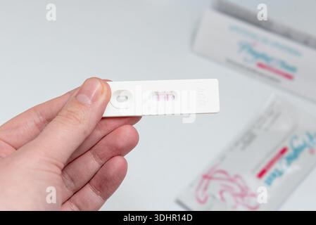 Frau, die zu Hause Schwangerschaftstest macht, Person, die medizinischen Teststreifen mit positivem Ergebnis in ihrer Hand hält Stockfoto
