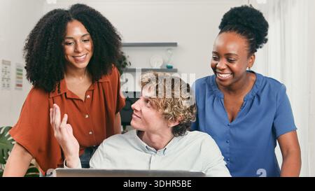 Vielfältiges Trio, das in einem modernen Startup-Office arbeitet, lächelt und Ideen während einer produktiven Session weitergibt Stockfoto