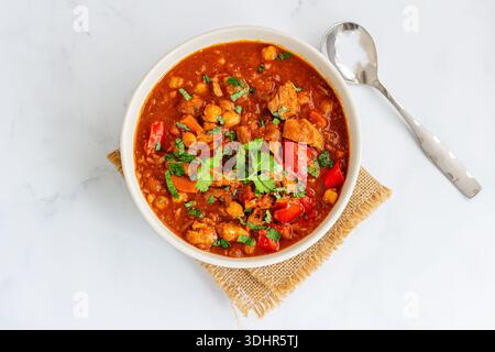 Traditioneller marokkanischer Hähncheneintopf in einer reichhaltigen Tomatensoße mit Kichererbsen, Paprika und aromatischen Gewürzen Stockfoto