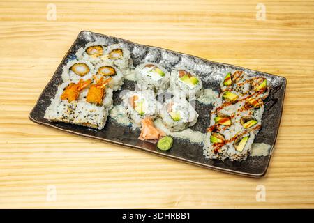 Uramaki-Rollen auf einem Holzbrett oder einer weißen Platte, die jeweils in sechs oder acht gleiche und ordentlich angeordnete Stücke geschnitten sind. Stockfoto