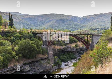 Eine malerische Moraca-Brücke überspannt eine felsige Schlucht in einer ruhigen Landschaft. Umgeben von Bäumen und Hügeln vermittelt die ländliche Landschaft Ruhe, Natur und Natur Stockfoto
