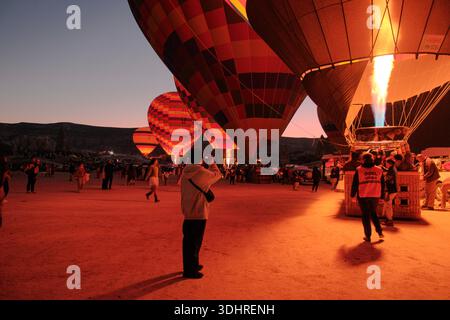 Kappadokien, Türkiye – 3. Oktober 2024: Heißluftballons schweben während einer Ballontour bei Sonnenaufgang über die felsige Landschaft Kappadokiens Stockfoto