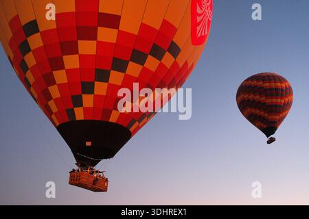 Kappadokien, Türkiye – 3. Oktober 2024: Heißluftballons schweben während einer Ballontour bei Sonnenaufgang über die felsige Landschaft Kappadokiens Stockfoto