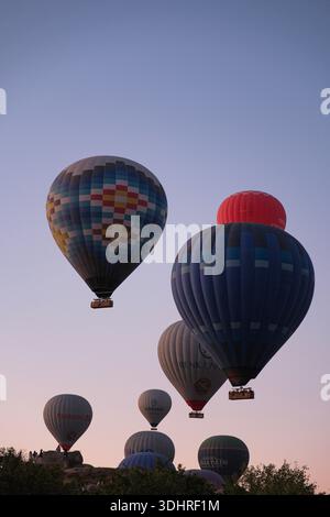 Kappadokien, Türkiye – 3. Oktober 2024: Heißluftballons schweben während einer Ballontour bei Sonnenaufgang über die felsige Landschaft Kappadokiens Stockfoto