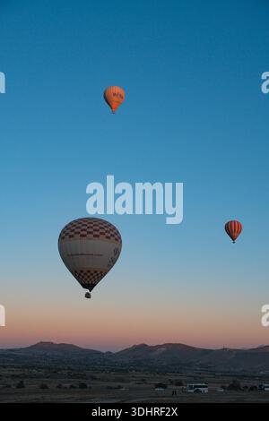 Kappadokien, Türkiye – 3. Oktober 2024: Heißluftballons schweben während einer Ballontour bei Sonnenaufgang über die felsige Landschaft Kappadokiens Stockfoto