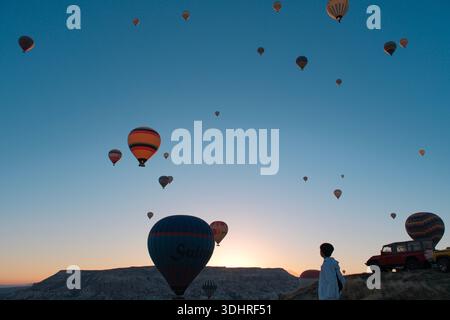 Kappadokien, Türkiye – 3. Oktober 2024: Heißluftballons schweben während einer Ballontour bei Sonnenaufgang über die felsige Landschaft Kappadokiens Stockfoto