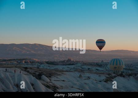 Kappadokien, Türkiye – 3. Oktober 2024: Heißluftballons schweben während einer Ballontour bei Sonnenaufgang über die felsige Landschaft Kappadokiens Stockfoto