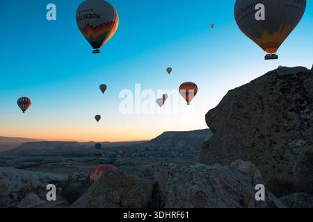 Kappadokien, Türkiye – 3. Oktober 2024: Heißluftballons schweben während einer Ballontour bei Sonnenaufgang über die felsige Landschaft Kappadokiens Stockfoto
