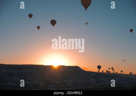 Kappadokien, Türkiye – 3. Oktober 2024: Heißluftballons schweben während einer Ballontour bei Sonnenaufgang über die felsige Landschaft Kappadokiens Stockfoto