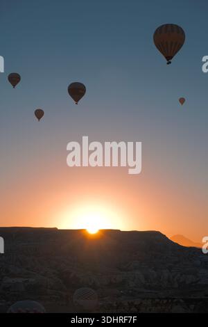 Kappadokien, Türkiye – 3. Oktober 2024: Heißluftballons schweben während einer Ballontour bei Sonnenaufgang über die felsige Landschaft Kappadokiens Stockfoto