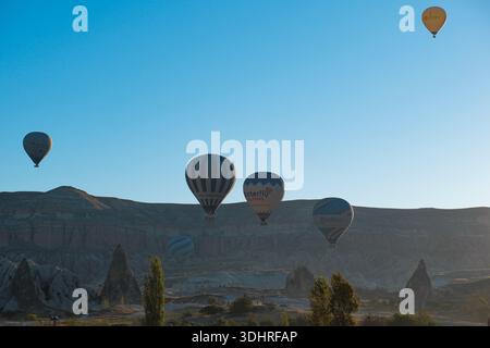 Kappadokien, Türkiye – 3. Oktober 2024: Heißluftballons schweben während einer Ballontour bei Sonnenaufgang über die felsige Landschaft Kappadokiens Stockfoto