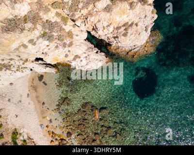 Aus der Vogelperspektive auf klares türkisfarbenes Wasser trifft auf felsige Küste mit untergetauchten dunklen Flecken und enthüllt Unterwassergelände. Elba Italien Stockfoto