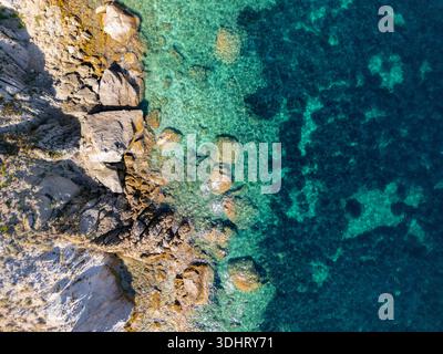 Blick aus der Vogelperspektive auf eine felsige Küste und klares türkisfarbenes Wasser mit natürlicher Schönheit und lebendiger Meereslandschaft. Elba Italien Stockfoto