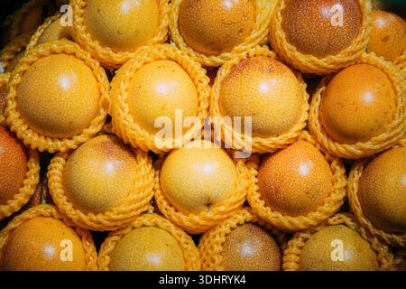 Gelbe Passionsfrüchte (granadilla), einzeln in Schaumschutznetze verpackt. Hochwertige Lagerung tropischer Früchte in Sanya, Hainan. Stockfoto