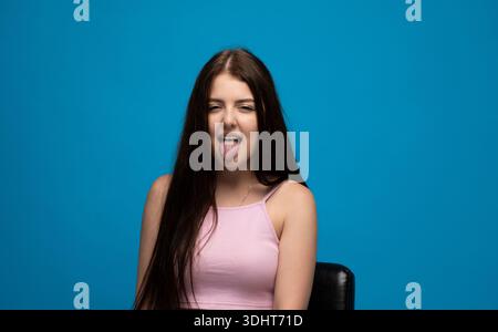 Eine verspielte junge Frau, die mit der Zunge ein komisches Gesicht macht Stockfoto