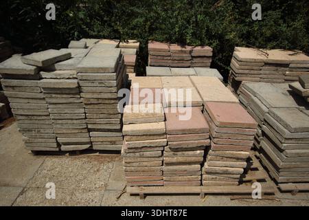 Gestapelte quadratische Betonplatten in Grau- und Terrakottatönen auf Holzpaletten für Landschaftsgestaltung Stockfoto