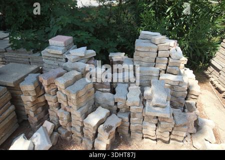Gestapelte Betonpflastersteine und graue rechteckige Gartenfliesen im Freien Stockfoto