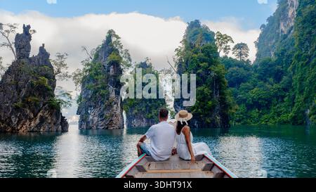 Zwei Reisende genießen einen ruhigen Moment auf einem Boot am Cheow Lan Lake in Khao Sok, Thailand. Umgeben von majestätischen Kalksteinklippen und üppigem Grün, ist die Landschaft fesselnd. || Modell freigegeben Stockfoto