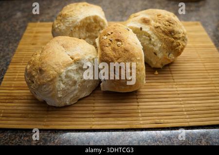 Vier rustikale frische Brötchen auf Bambusmatte Stockfoto