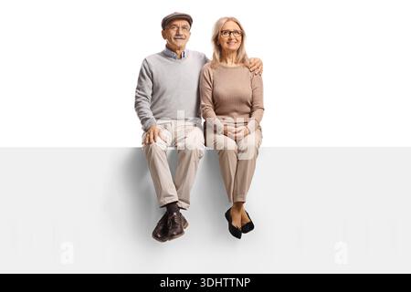 Glückliches, reifes Paar aß auf einer leeren Tafel mit Armen um einander isoliert auf weißem Hintergrund Stockfoto