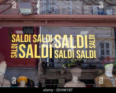 Cremona, Italien, 9. Januar 2026 das leuchtende Fenster mit leuchtenden Saldi-Schildern und Bannern lockt Kunden mit Sonderangeboten und Rabatten für Stockfoto