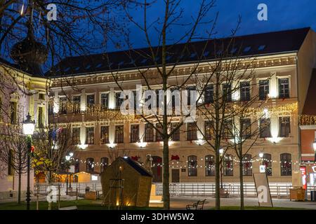 Das Bild zeigt die Fußgängerzone in Vinkovci während der Adventsveranstaltung in Vinkovci. Eine festliche europäische Straßenszene zur blauen Stunde mit einem Rosa Stockfoto